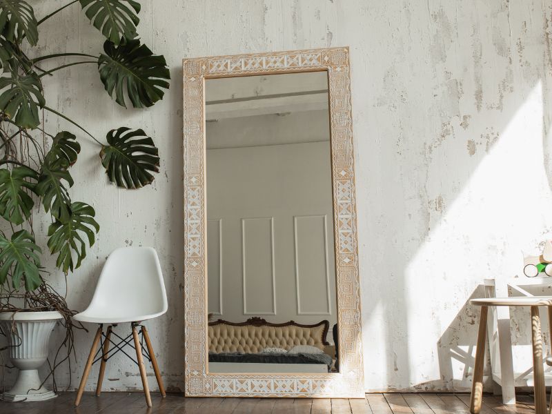 Miroir contre 1 mur blanchi avec plante et tabiurate decoratif