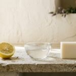 Demi-citron, bol d'eau claire et savon ivoire alignés sur une pierre : l'échelle du pH en objets - illustration, La Savonnerie de Nyons