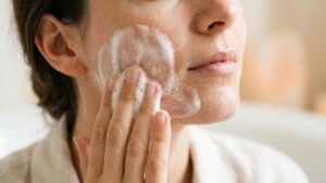 Gros plan d'une joue : une main applique une mousse de savon dense et onctueuse - La Savonnerie de Nyons