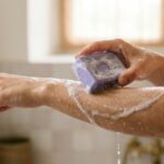 Avant-bras mouillé couvert de mousse, une main frotte un savon de la Savonnerie de Nyons contre l'autre, variante A - La Savonnerie de Nyons